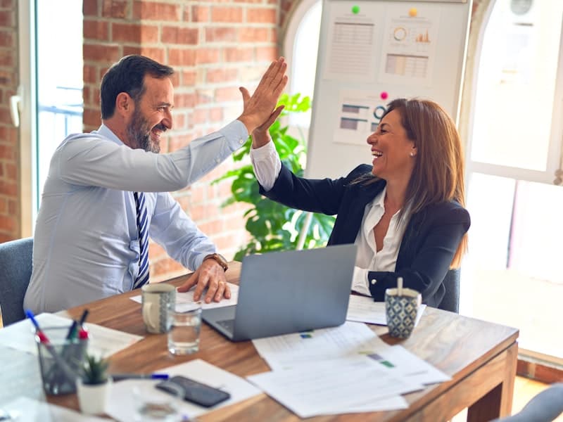 Two colleagues celebrating a win together at their desk