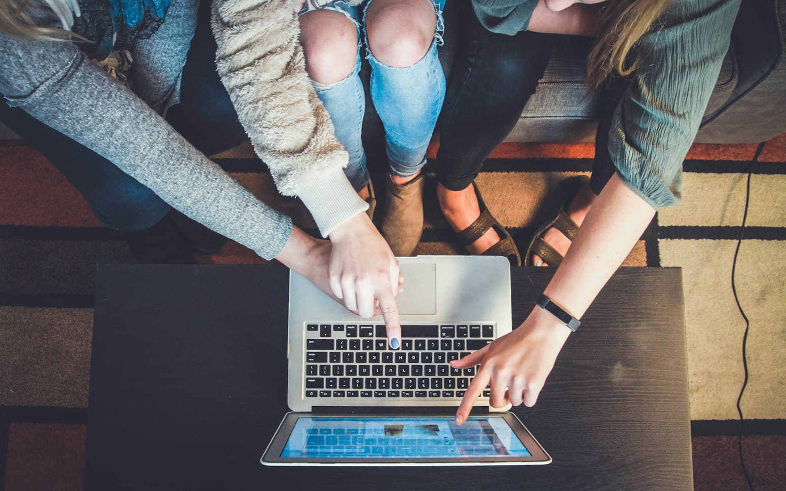 Three people pointing at one laptop — when the business number lives on one phone, the firm’s memory lives there too.