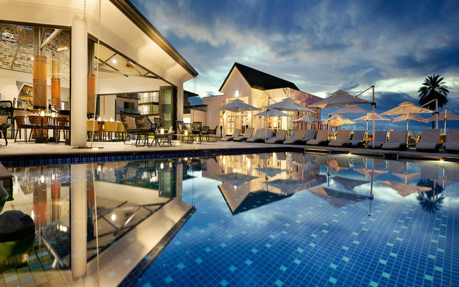 Lounge chairs by a pool at evening — pre-arrival is a CRM beat, not a mail-merge.