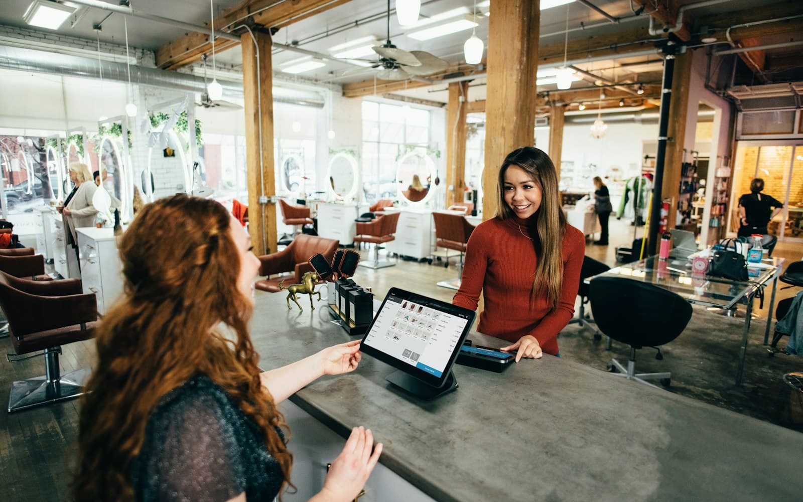 A salon desk with a booking screen — the shop already has a system of record; WhatsApp still needs to sit on the same person.