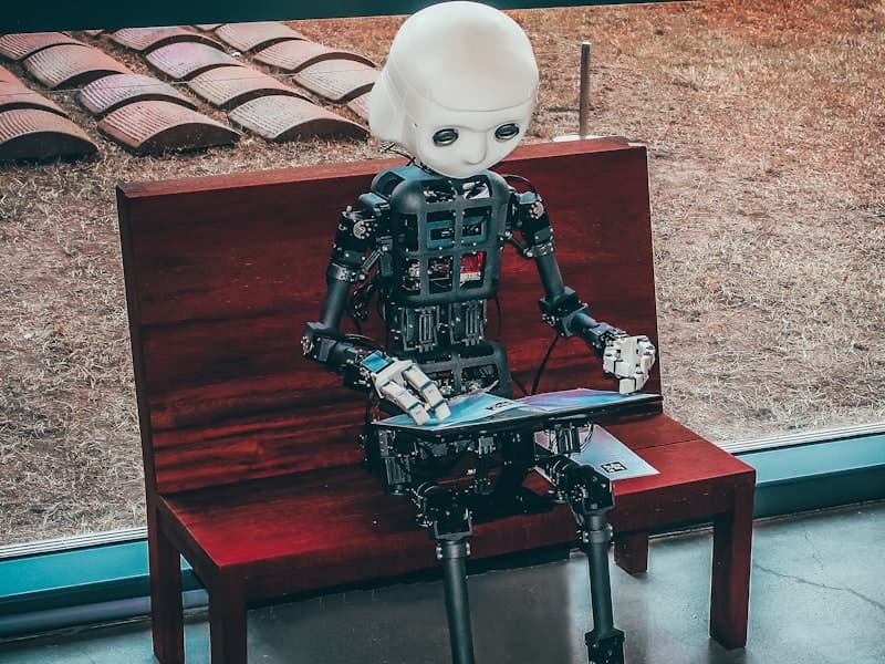 A humanoid robot sitting on a bench, evoking an AI assistant