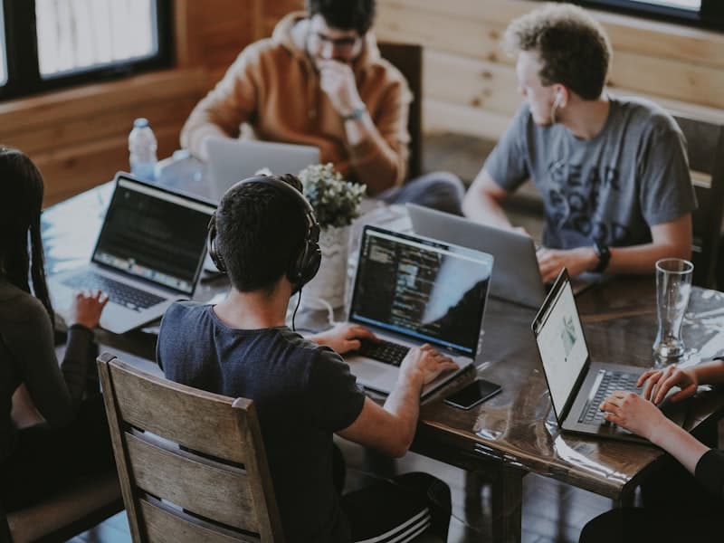 A team of colleagues working together at laptops around a shared table